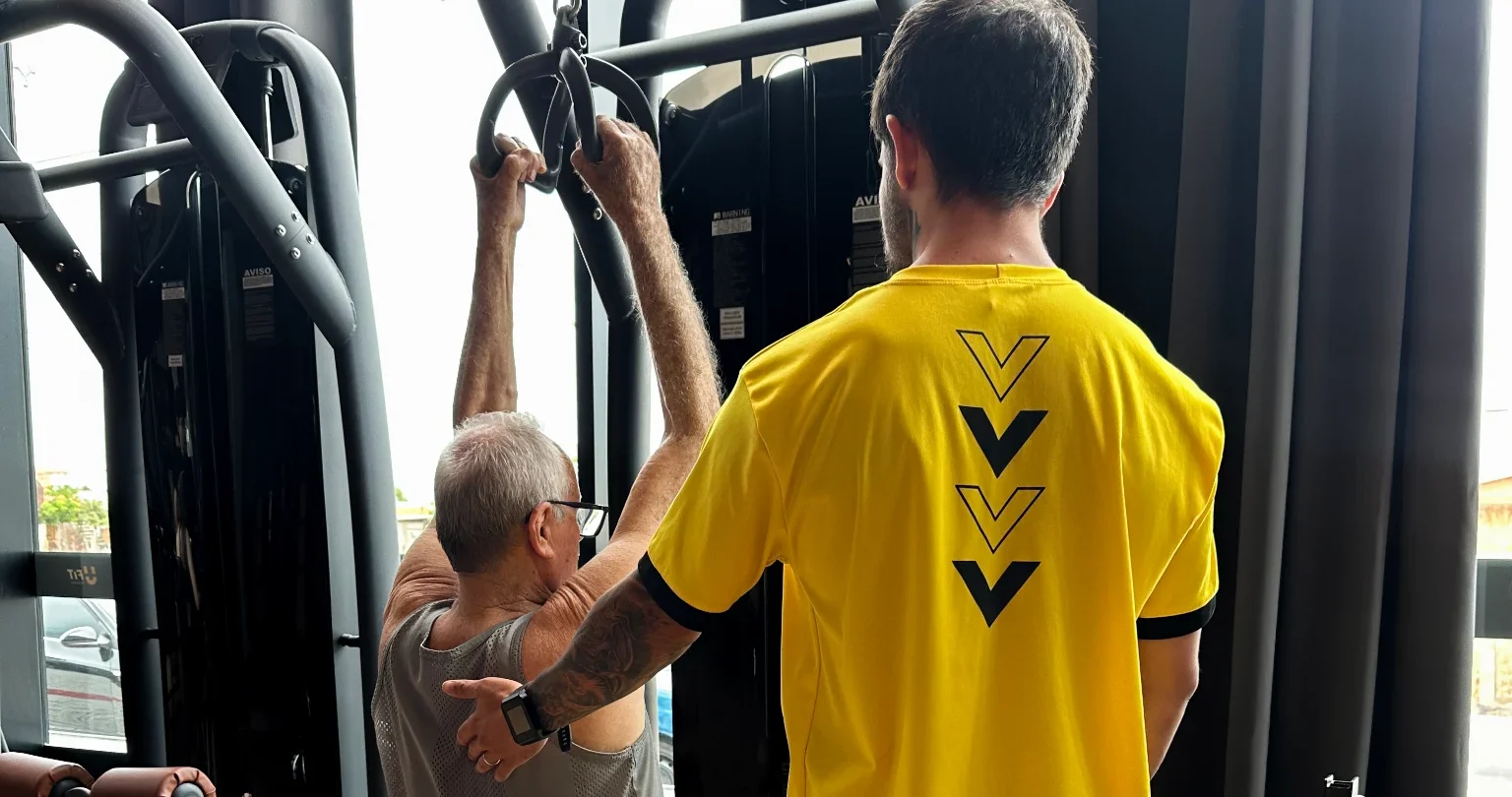 Professor orientando aluno mais velho na máquina